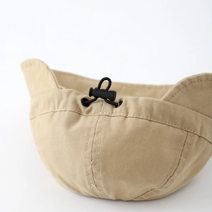 Detalle del cordón ajustable y hebilla en el gorro de pescador de lona caqui para bebé