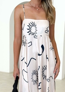 Detail of light pink summer dress featuring black sun prints and thin shoulder straps