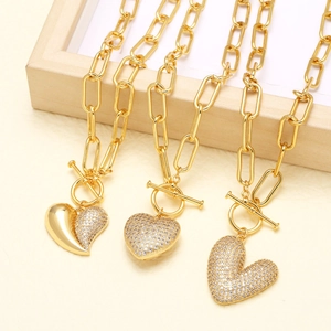 Golden heart necklaces with full zircon pendants and OT toggle clasp on textured background