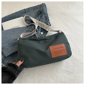 Detail of green nylon crossbody bag with patterned wide strap and fashion leather patch