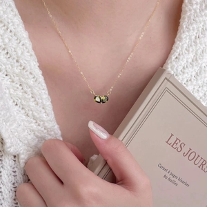 Elegant 925 silver necklace with green pear-shaped stones worn with a white cardigan