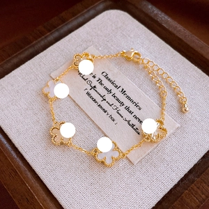 Detail of gold floral bracelet with white clover motifs on a luxury jewelry box lining