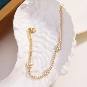 Detailed view of gold five-petal flower bracelet with micro-pave zircons on a white tray