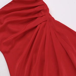 Detailed close-up of vibrant red satin fabric with elegant pleated texture and silky sheen
