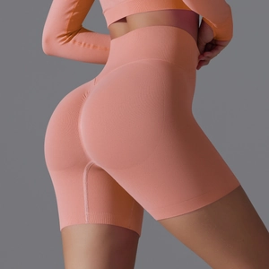 Detail showing seamless high-waist yoga shorts in coral pink with ribbed texture fabric