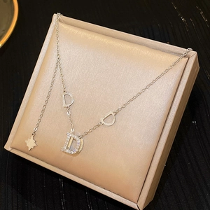 Elegant silver D-letter pendant necklace with zircons on a textured jewelry box