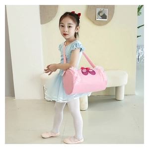 Detailed view of pink cylinder ballet bag with lace trim and bow on a little dancer