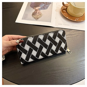 Close-up of long wallet with black and white woven pattern and golden zipper details
