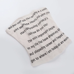 Detail eines beigen Strick-Tube-Tops mit schwarzem Buchstaben-Print auf der Vorderseite