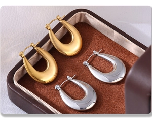 Detail view of U-shaped gold and silver earrings placed in a luxury leather jewelry box
