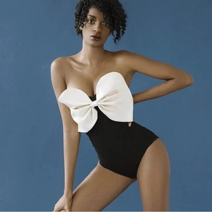 Maillot de bain noir à une épaule avec un grand nœud blanc sur fond bleu élégant