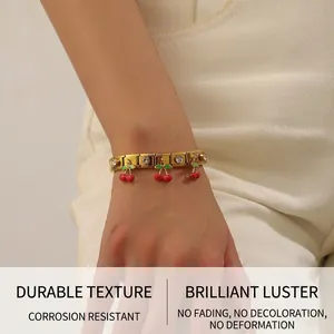 Detail of gold-plated stainless steel bracelet with red cherry pendants and crystals