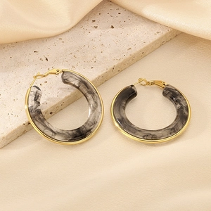 Detail of C-shaped resin hoop earrings with grey marble texture and gold plated edges