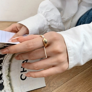 Detail of gold-plated pearl open ring set worn on finger for a minimalist fashion look