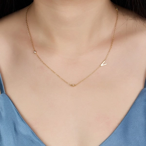Detail of a gold S925 silver necklace with V-pendant and zircon stones on a model