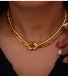 Close-up of gold double-layer snake chain necklace with knot detail on model neck