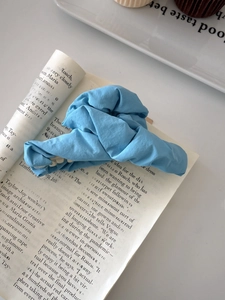Sky blue pleated fabric hair claw clip on a book, elegant aesthetic hair accessory