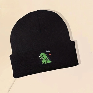 Close-up of green dinosaur embroidery with Hello text on a black knitted beanie