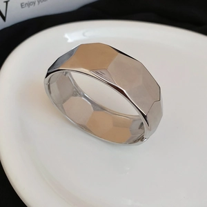 Macro shot of silver wide geometric bangle showing irregular faceted metal surface details