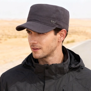 Dark grey cotton flat top cap with metallic sports style badge shown in outdoor setting