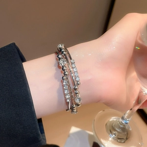 Macro detail of silver layered wrap bracelet with sparkling crystals on a model's wrist