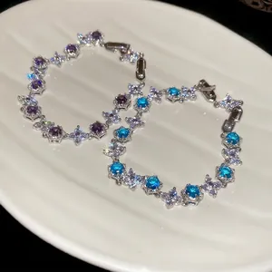 Exquisite flower zircon bracelets in blue and purple, set in a white ceramic dish
