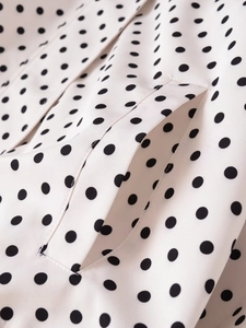 Detalle de camisa blanca con lunares negros mostrando el bolsillo y la costura
