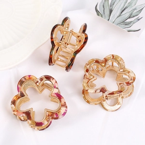 Three acrylic floral hair claws in amber, marble, and flower patterns on white fabric