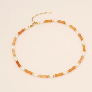 Bamboo style natural stone necklace with pearls and gold beads on a beige surface