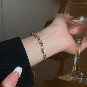 Close-up of a colorful gemstone bracelet with adjustable gold chain on model's wrist