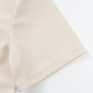 Detalle del tejido de nido de abeja beige en el conjunto de camisa y pantalón corto