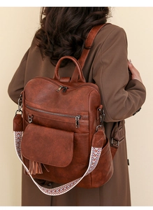 Detail view of brown PU leather backpack with tassel and colorful woven shoulder strap