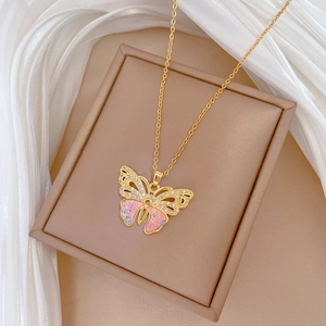 Elegant gold butterfly necklace with pink and blue stones on beige leather jewelry box