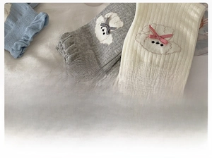 Close-up of cotton socks with puppy embroidery, bow accents, and ruffle cuffs
