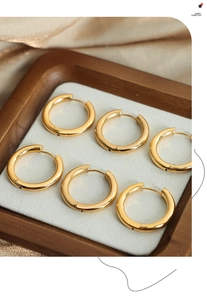 Detailed view of three pairs of 18K gold plated titanium steel hoop earrings on white velvet