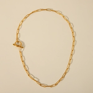 Close-up of golden paperclip link chain necklace with toggle clasp on flat surface