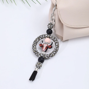 Silicone leopard cow head keychain with black tassel and rhinestones on beige bag