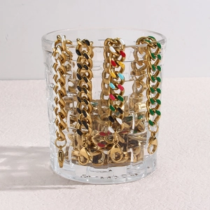 Golden stainless steel Cuban chains with colorful enamel charms on a glass edge
