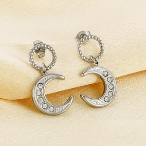 Detailed macro view of silver crescent moon earrings with inlaid crystals on silk