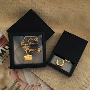 Detailed view of golden necklace and earrings inside a black PE film jewelry box