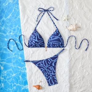 Detail of navy blue halter bikini with gold starfish charm on textured beach background