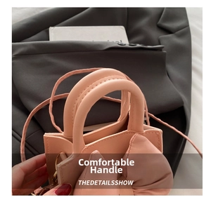 Close-up of pink leather bucket bag featuring a large decorative bow and golden hooks