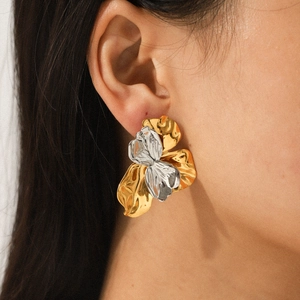 Close-up of dual-tone gold and silver hammered flower earrings worn by a model