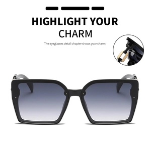 Detail view of large square black sunglasses with gold metal hinges and gradient lenses
