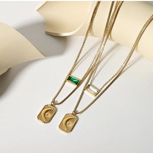 Detail of layered gold necklaces featuring sun moon pendants and green zircon crystals