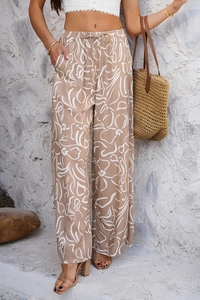 Détail d'un pantalon bohème à jambes larges avec motif floral blanc sur tissu brun