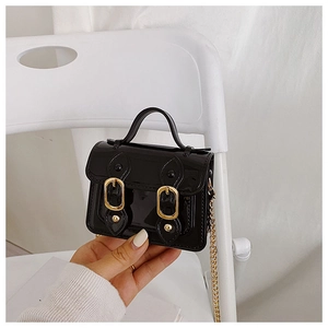 Detail of glossy black patent leather mini crossbody bag with gold chain and double buckles