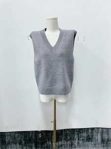 Detail of grey V-neck knitted vest showing the chunky knit texture and ribbed hemline