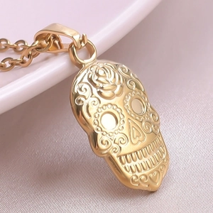 Macro shot of 18k gold plated sugar skull pendant with floral relief on pink silk
