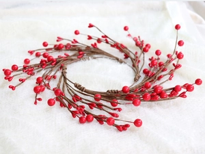 Close-up of artificial red berry wreath candle ring with realistic brown branches